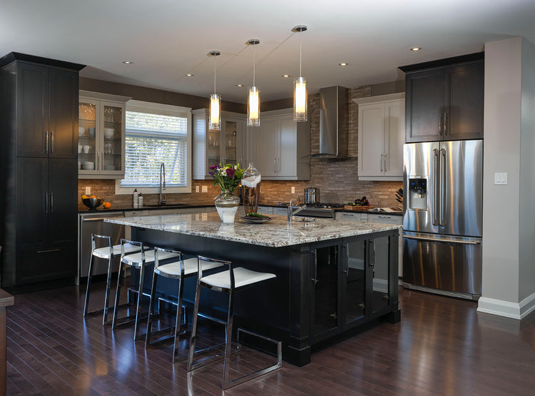 Modern kitchen with a large island, pendant lighting, stainless steel appliances, and dark cabinetry with a marble countertop.