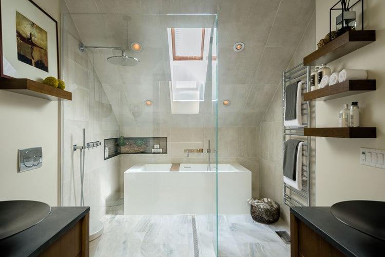 Modern bathroom with a glass-enclosed shower and tub, skylight, and built-in shelving with towels and decor.