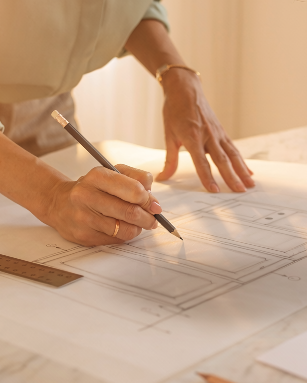 Person drawing on a blueprint with a pencil and ruler.