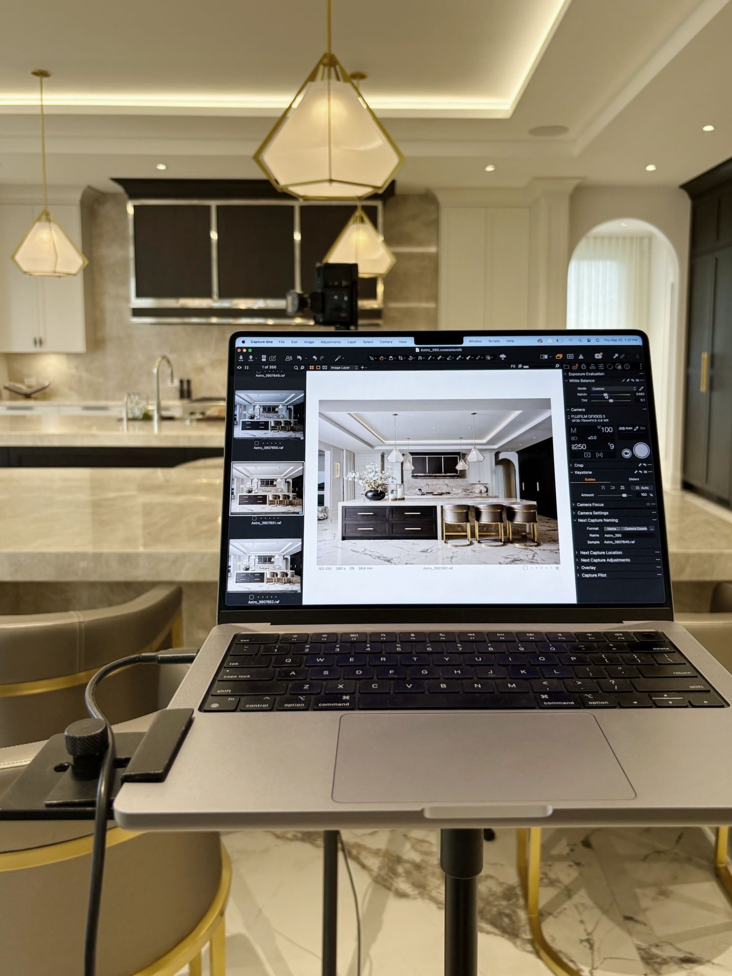 Laptop on a stand displaying interior design software in a modern kitchen.