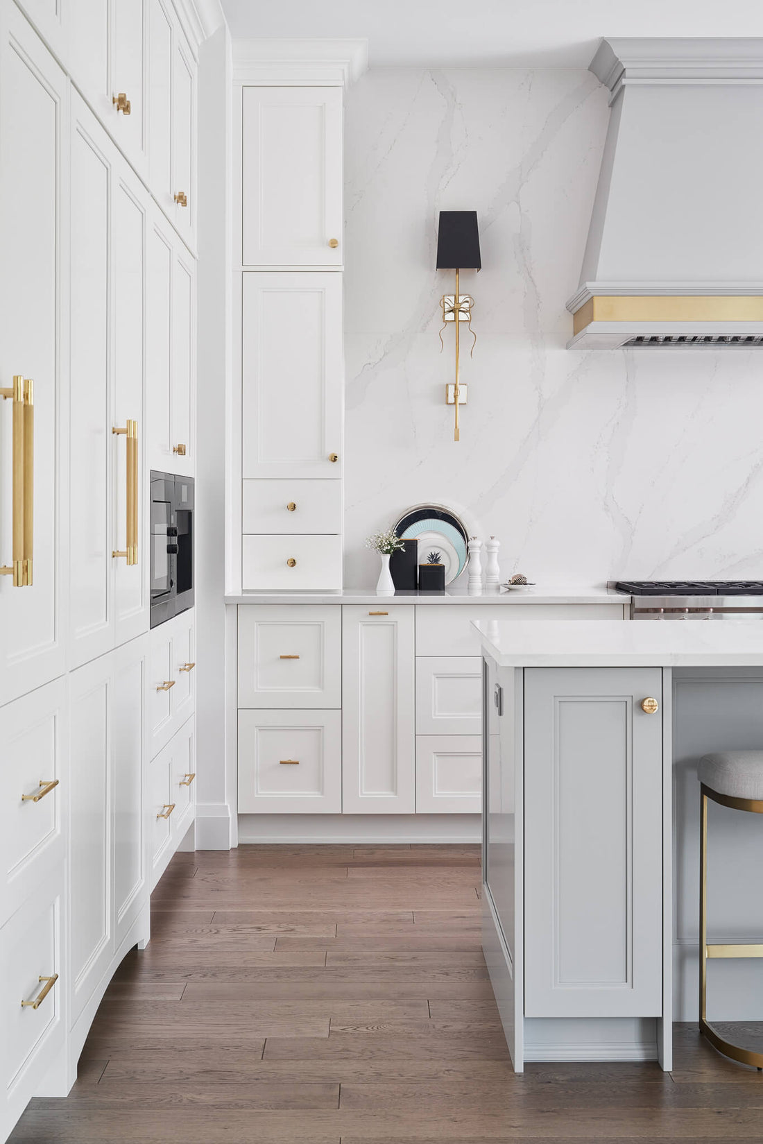Bright white kitchen with gold hardware, marble backsplash, and a soft gray island with classic cabinetry.