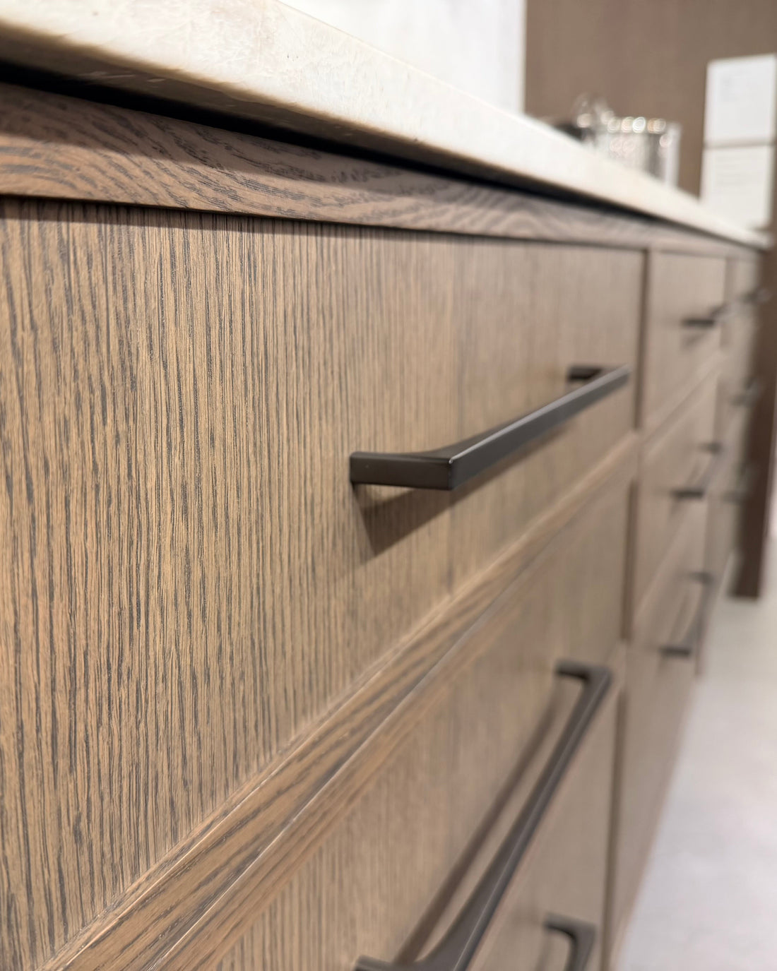 Close-up of wooden kitchen cabinets with black handles in a modern kitchen setting.