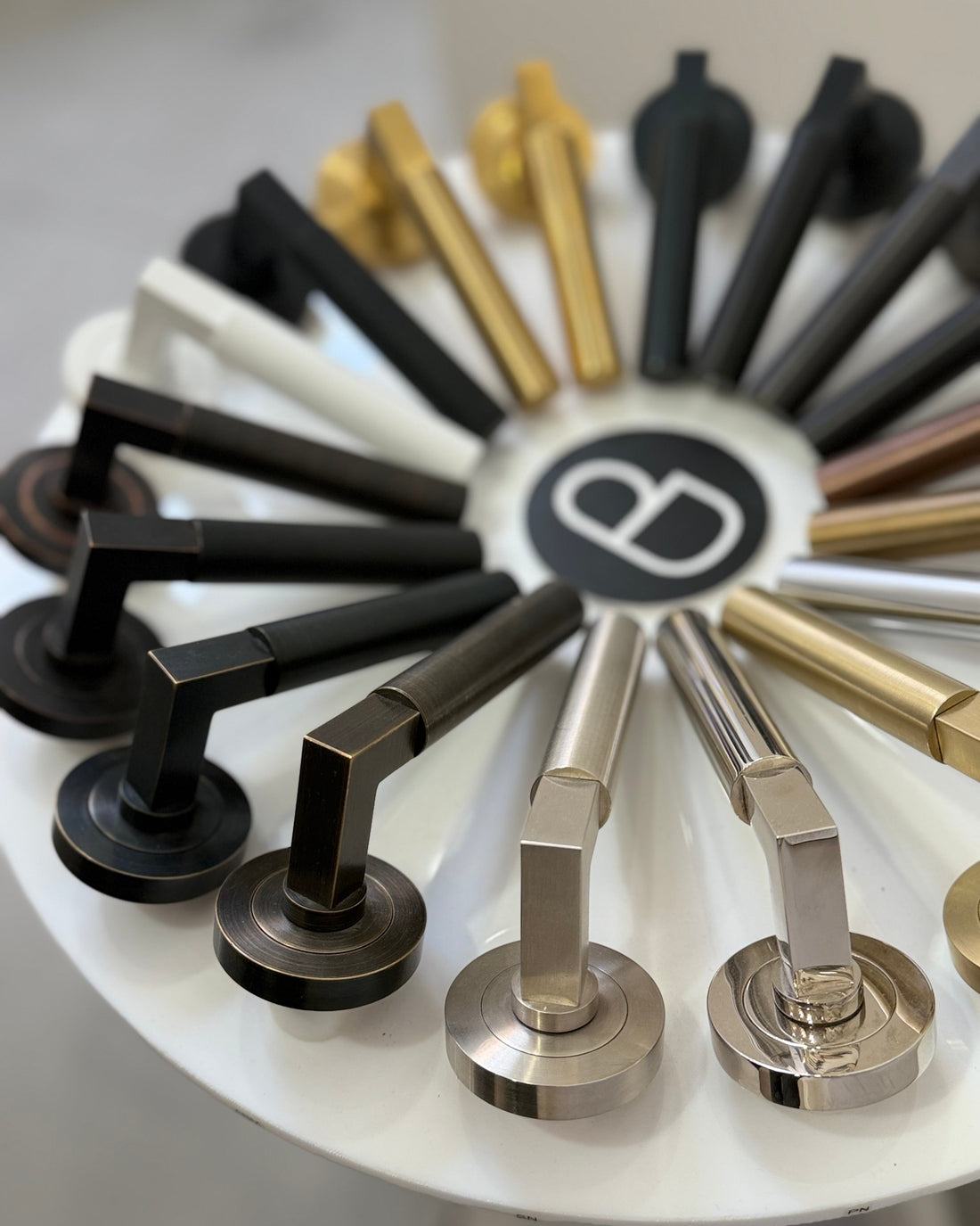 Set of door handles in various finishes on a display stand with a brand logo.