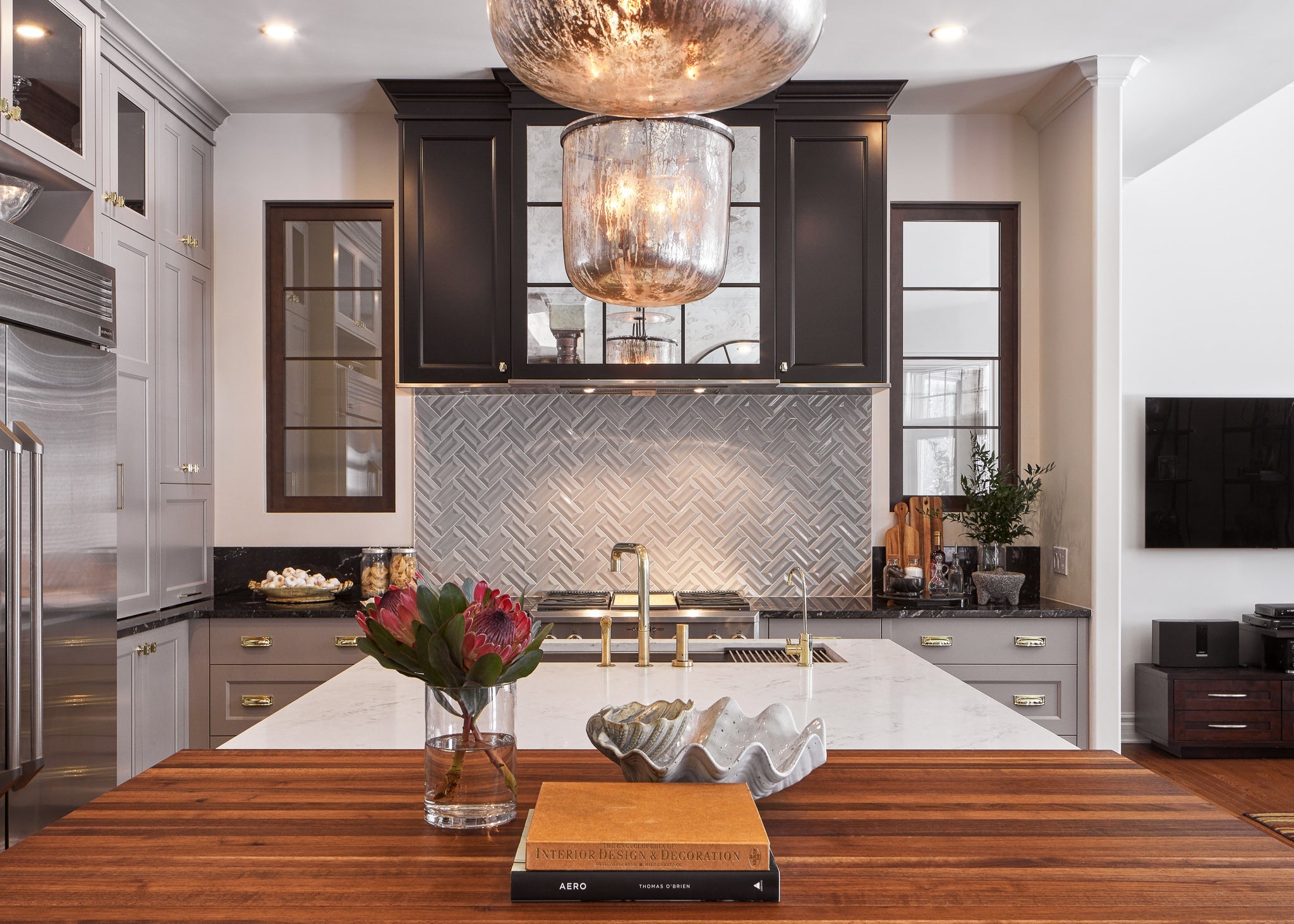 Modern kitchen with wooden island, glass pendant lights, and decorative elements.