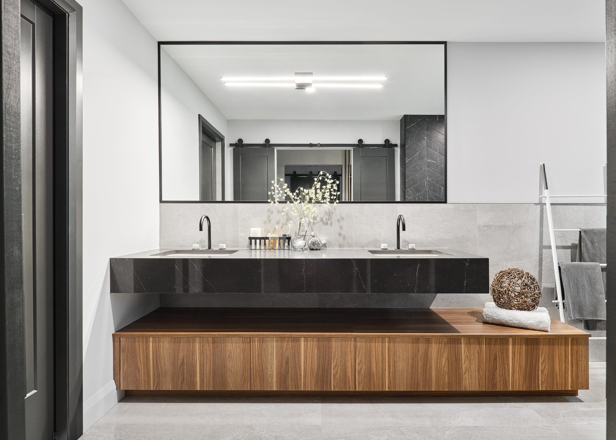 Modern bathroom with a large mirror, sink, and wooden vanity.
